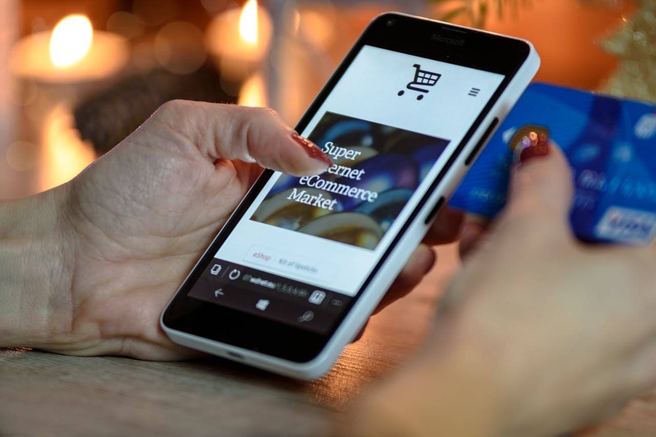 hero-img-02 Woman using smartphone for online shopping with credit card in hand, festive background lighting.