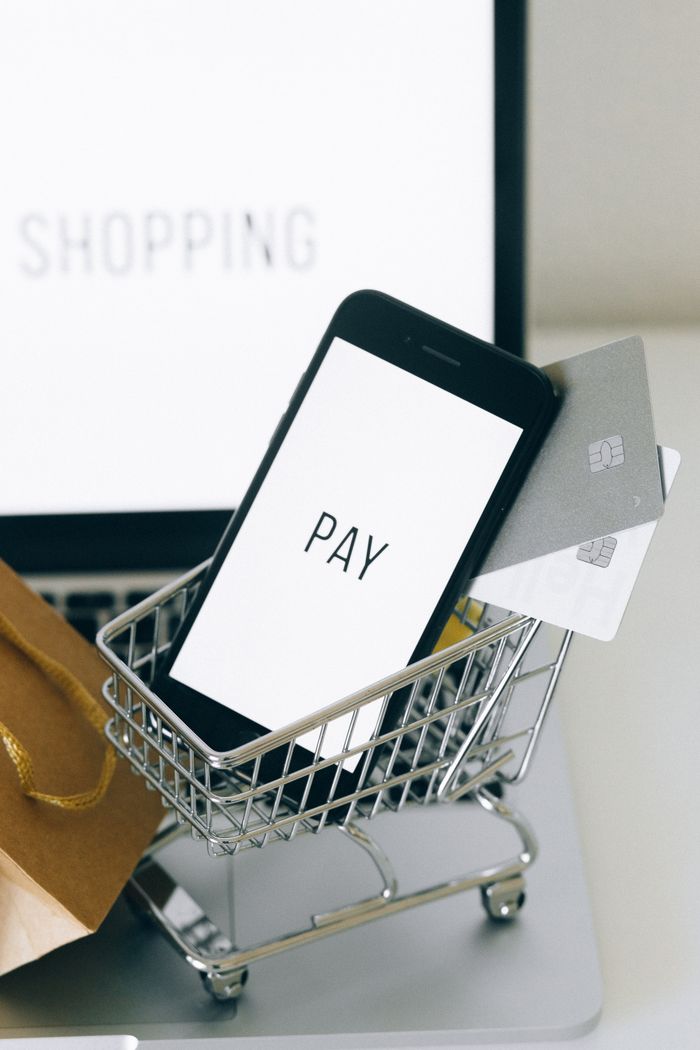 why-choose-us Smartphone in a miniature shopping cart symbolizes mobile shopping and online transactions.